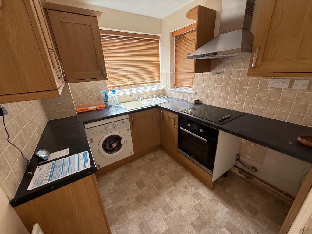 Lot: 111 - END-TERRACE ONE-BEDROOM HOUSE - Kitchen with built in electric hob and oven space for washing machine and fridge